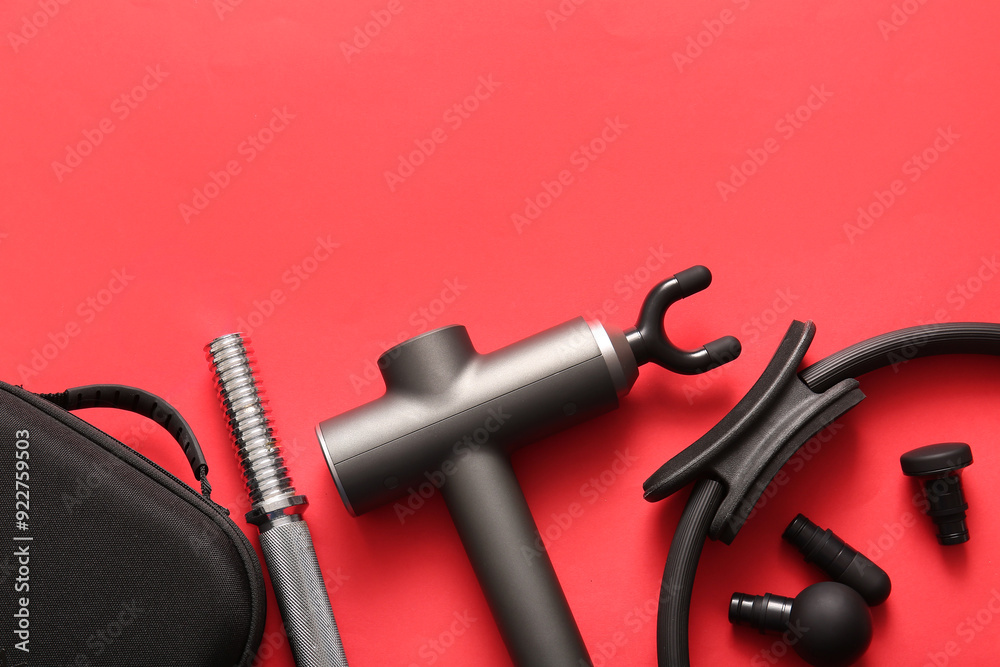 Composition with percussive massager and sports equipment on red background Composition with percussive massager and sports equipment on red background