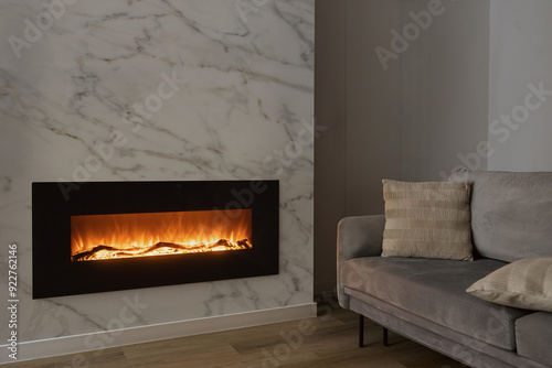 Modern electric fireplace with marble wall and sofa in room