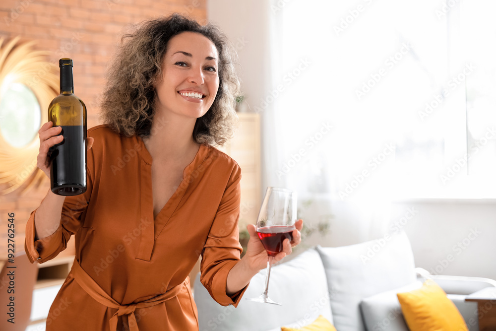 Beautiful middle-aged woman with bottle and glass of red wine at home Beautiful middle-aged woman with bottle and glass of red wine at home