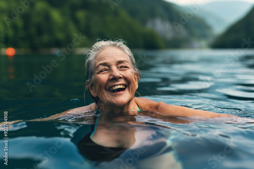 Fototapeta Naklejka Na Ścianę i Meble -  Active senior woman swimming in lake outdoors in nature, laughing