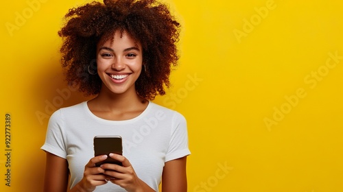 Smiling Woman Holding Smartphone Wearing Yellow Shirt Against Yellow Background