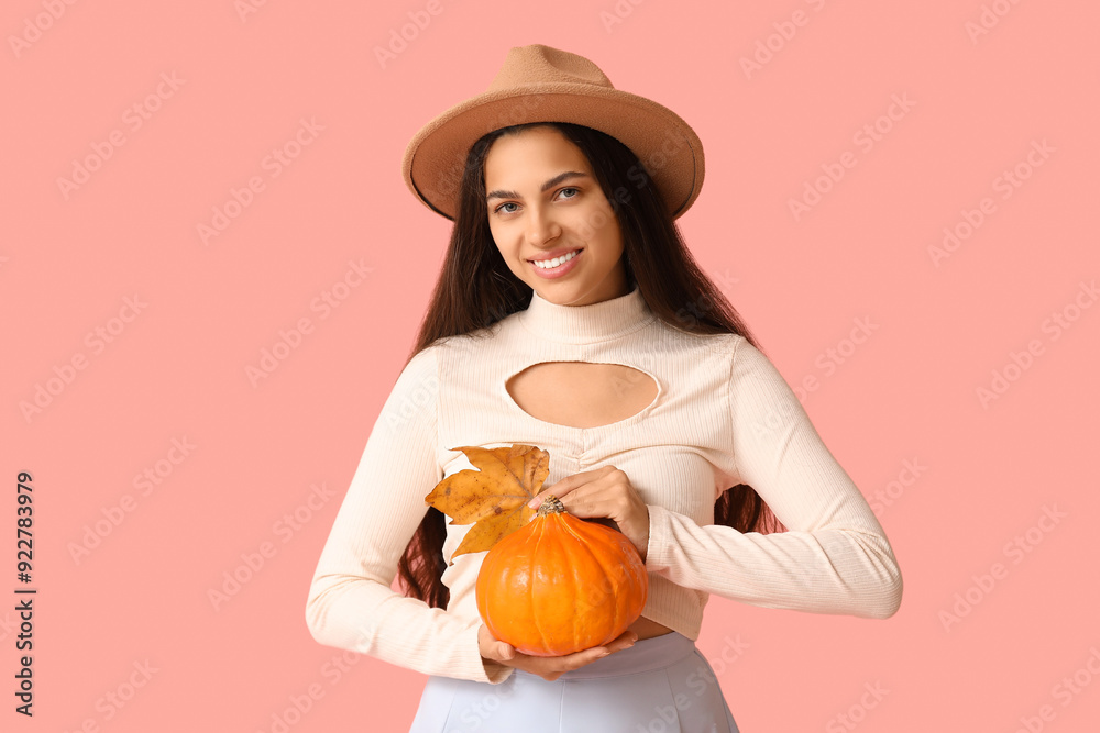 Stylish young woman with fresh pumpkin and autumn leaf on pink background Stylish young woman with fresh pumpkin and autumn leaf on pink background