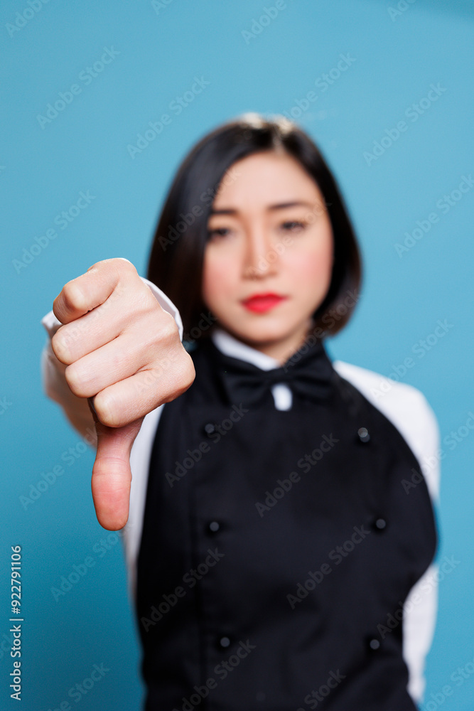 Dissatisfied asian waitress showing thumb down sign, expressing negative feedback and disapproval portrait. Receptionist displaying bad service experience concept and looking at camera Dissatisfied asian waitress showing thumb down sign, expressing negative feedback and disapproval portrait. Receptionist displaying bad service experience concept and looking at camera