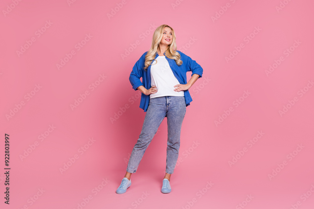 Full length photo of charming positive woman wear blue shirt looking empty space isolated pink color background Full length photo of charming positive woman wear blue shirt looking empty space isolated pink color background