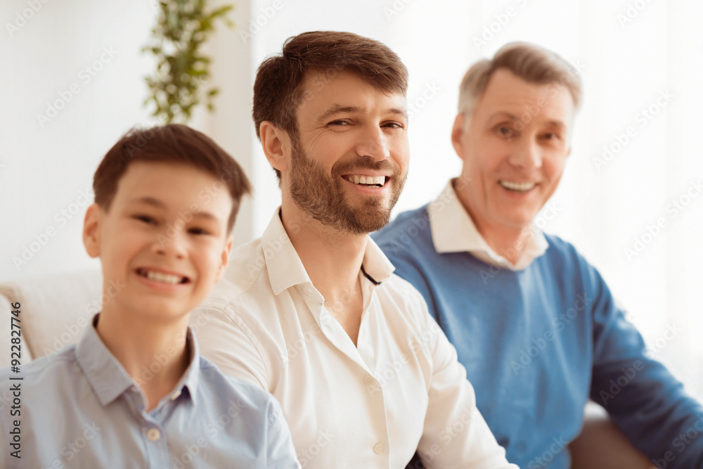 Male Generations. Happy Middle-Aged Man With Little Son And Elderly Father Smiling At Camera Sitting On Sofa Indoor. Selective Focus Male Generations. Happy Middle-Aged Man With Little Son And Elderly Father Smiling At Camera Sitting On Sofa Indoor. Selective Focus