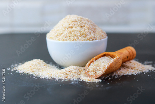 Psyllium Husk (Isabgol) in a bowl with a wooden scoop on a black background photo