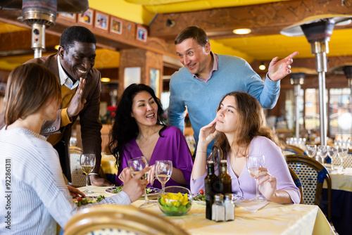 Smiling men invite women to dine for their table in the restaurant