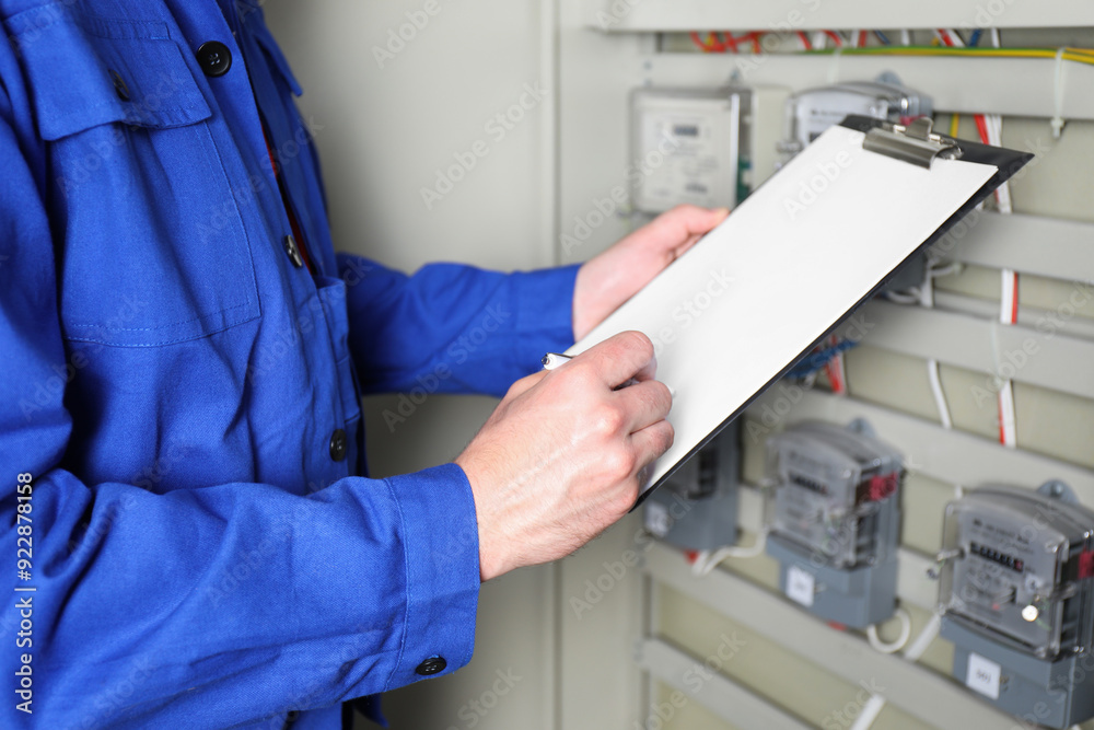 Technician worker with clipboard inspecting electricity meter, closeup Technician worker with clipboard inspecting electricity meter, closeup
