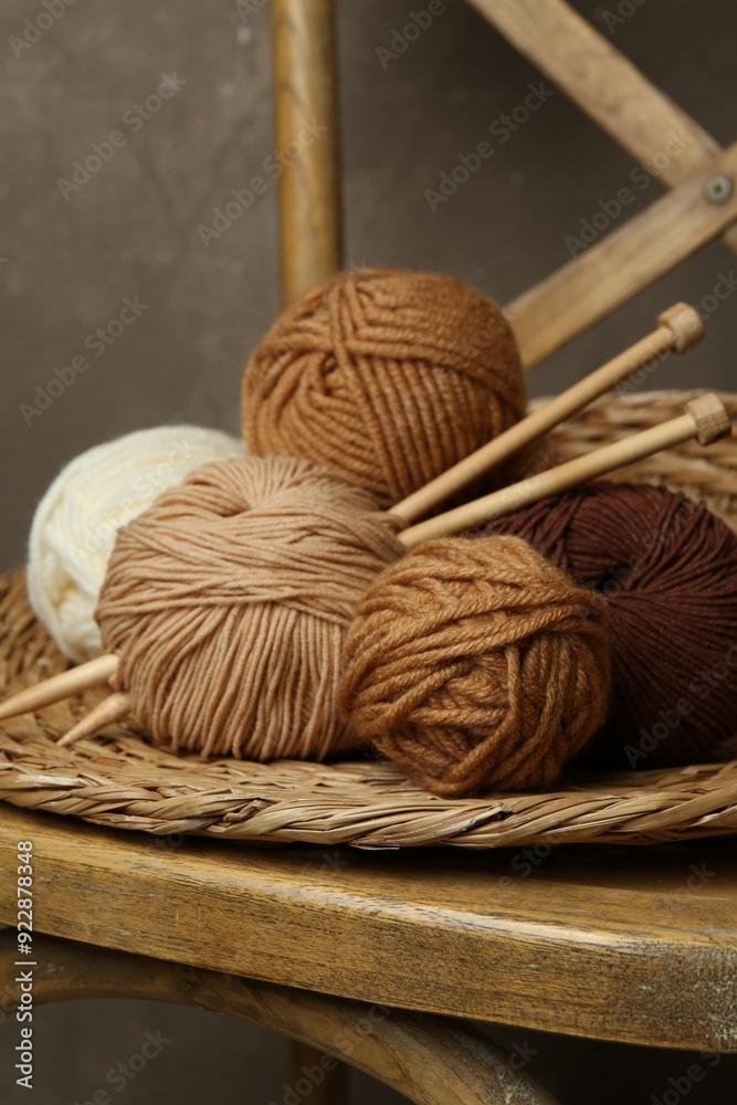 Skeins of different yarn, knitting needles and wicker mat on chair Skeins of different yarn, knitting needles and wicker mat on chair