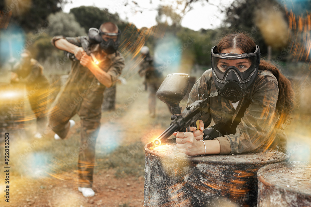 Fototapeta premium Paintball players of one team in camouflages and masks aiming with gun in shootout playing field