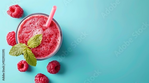 Glass of red raspberry smoothie on blue background