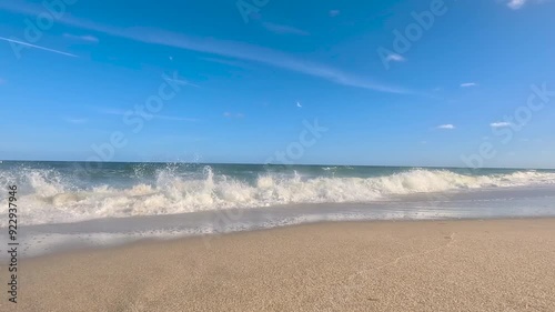 Camera tracks across sand into oncoming surf at Florida beach