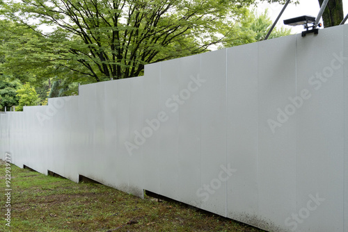 A long, empty blank white construction barrier or fence wall made up of several panels joined together, for temporary work sites in a park. photo