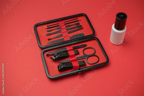 Black Manicure Set with Nail Tools in Red Case and Nail Polish Bottle on Red Background photo