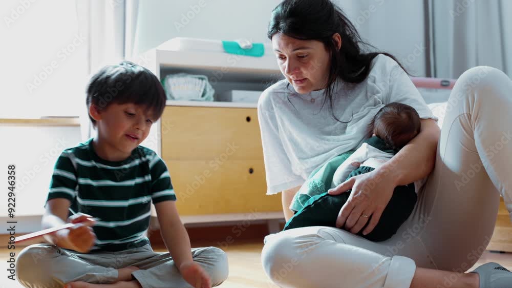 Mother sits on floor with newborn in arms, helping her young boy with a homeschool activity, creating an engaging and warm family scene focused on learning, togetherness, and love Mother sits on floor with newborn in arms, helping her young boy with a homeschool activity, creating an engaging and warm family scene focused on learning, togetherness, and love