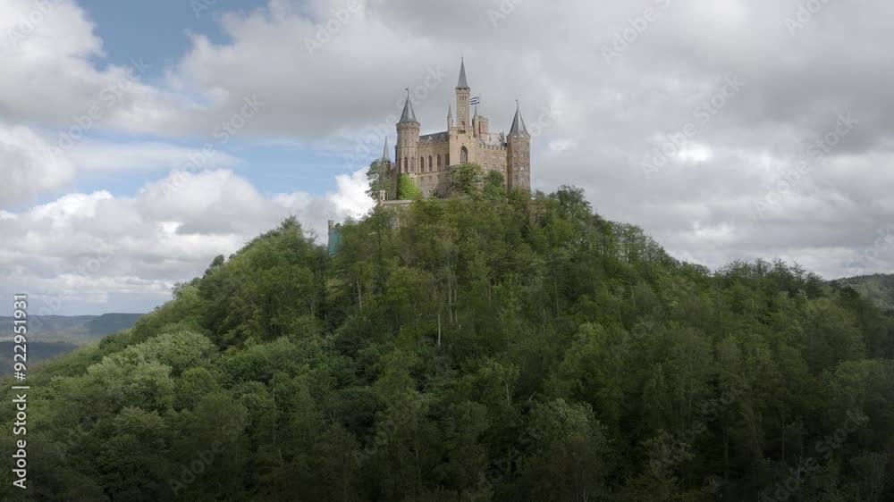 Hohenzollern Burg Castle standing majestically on a forest-covered hill under a cloudy sky, drone aerial orbit Hohenzollern Burg Castle standing majestically on a forest-covered hill under a cloudy sky, drone aerial orbit