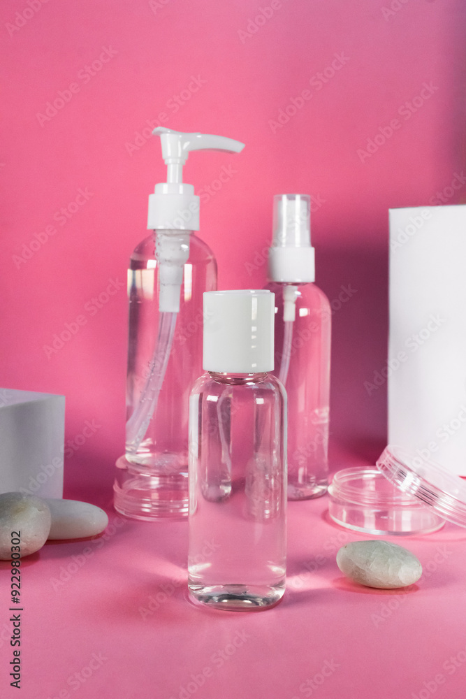 Set of transparent plastic bottles with white caps and pump, arranged on a pink background Set of transparent plastic bottles with white caps and pump, arranged on a pink background