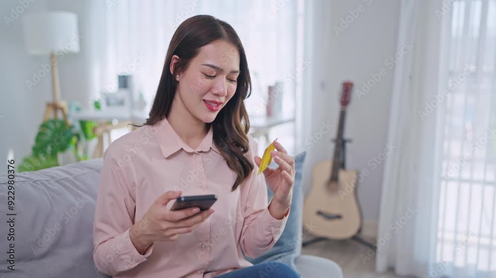 Asian woman using mobile phone shopping online in living room at home. Asian woman using mobile phone shopping online in living room at home.