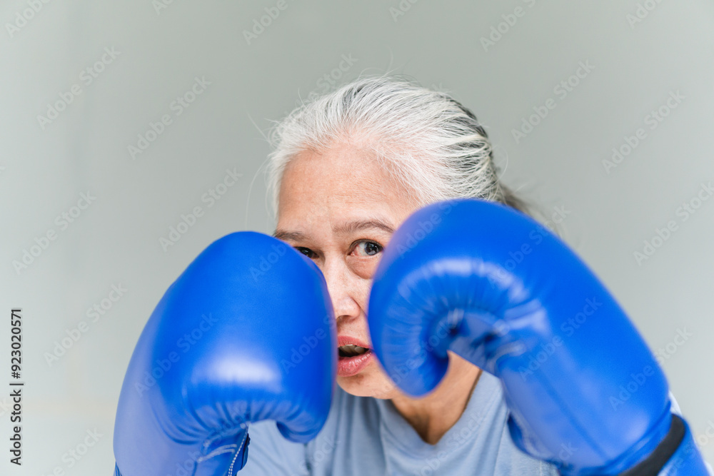 Close up of Asian senior sportswoman boxing while working out with gray background