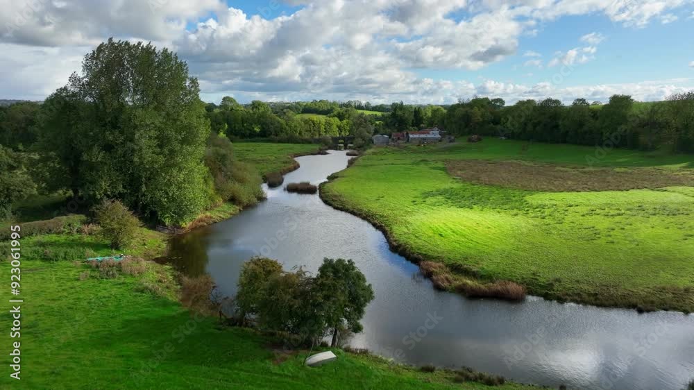 Finn River, County Monaghan, Ireland, September 2022. Drone pushes forward over bend in river soaring up across old bridge rising over pastures and grasslands on beautiful day. Finn River, County Monaghan, Ireland, September 2022. Drone pushes forward over bend in river soaring up across old bridge rising over pastures and grasslands on beautiful day.