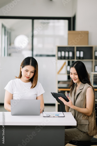 Two Asian businesswoman discuss investment project working and planning strategy with tablet laptop computer