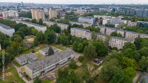 Drone photography of old multistory houses surrounded by trees during cloudy summer day.