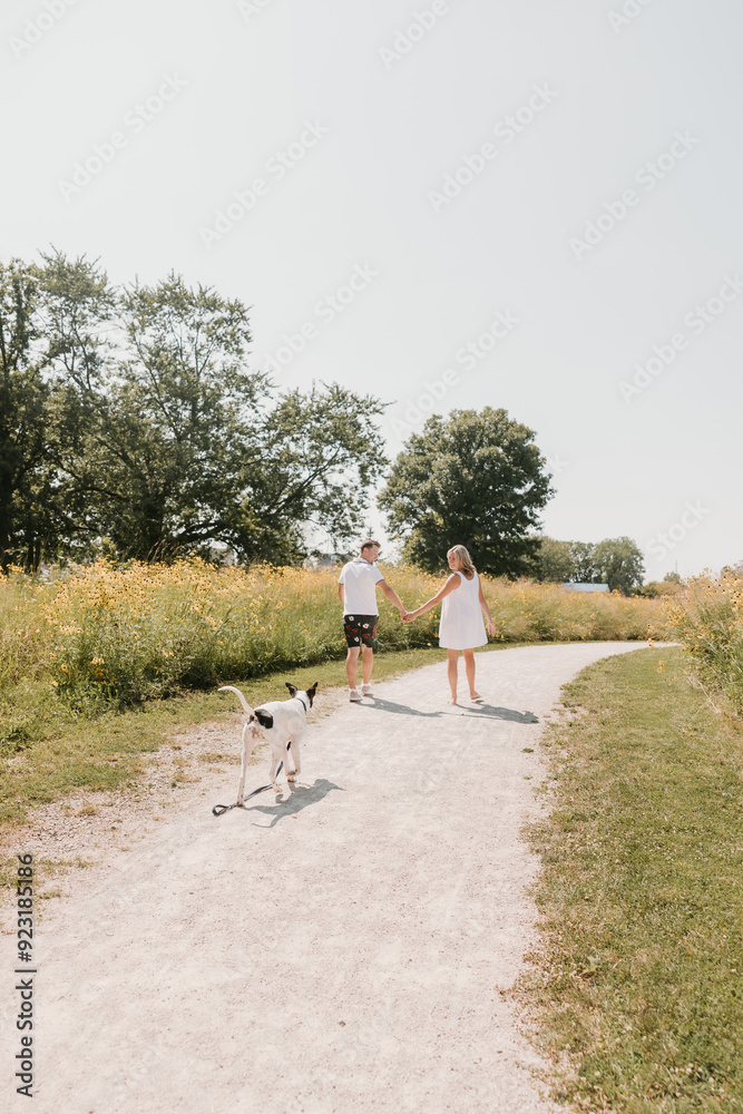 Young Couple walking with dog on path lined with wildflowers Young Couple walking with dog on path lined with wildflowers