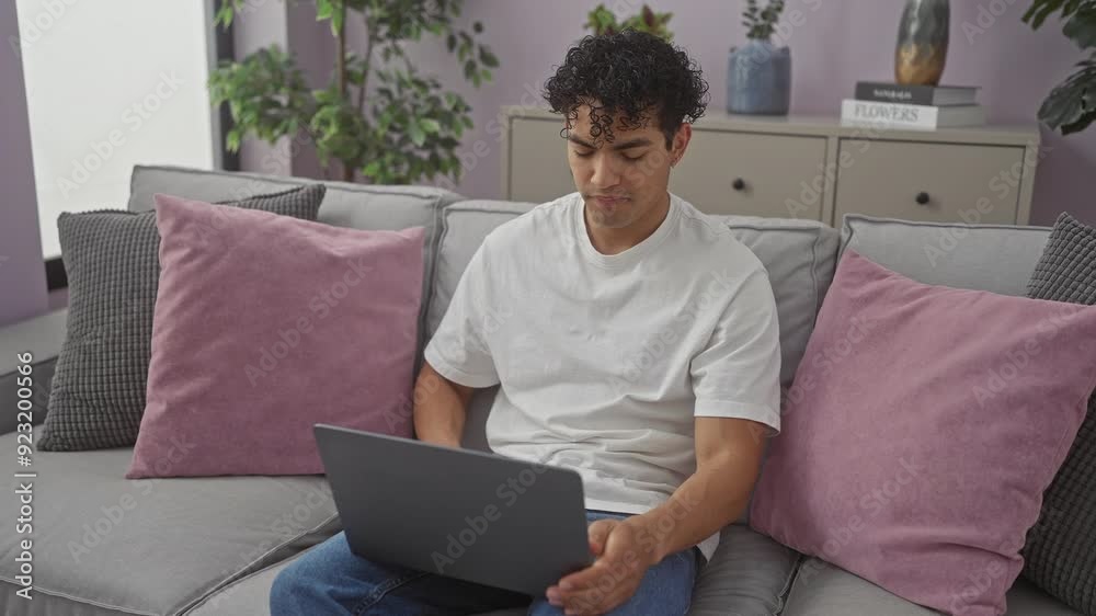 Handsome hispanic man using laptop on sofa in a modern living room Handsome hispanic man using laptop on sofa in a modern living room