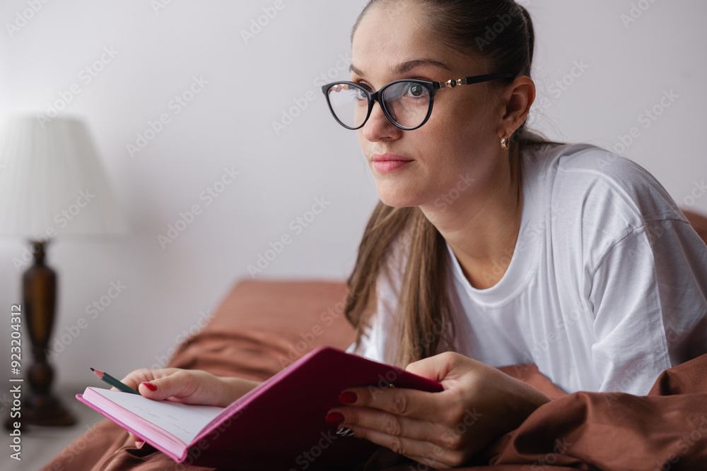 Woman Wearing Glasses Writing in Journal on Bed