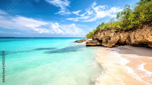 Gentle waves lap at the shoreline as vibrant turquoise waters meet soft white sand beneath a clear blue sky