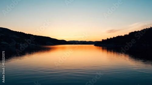 Golden hues reflect on still waters as the sunset casts a warm glow across the landscape, creating a peaceful atmosphere