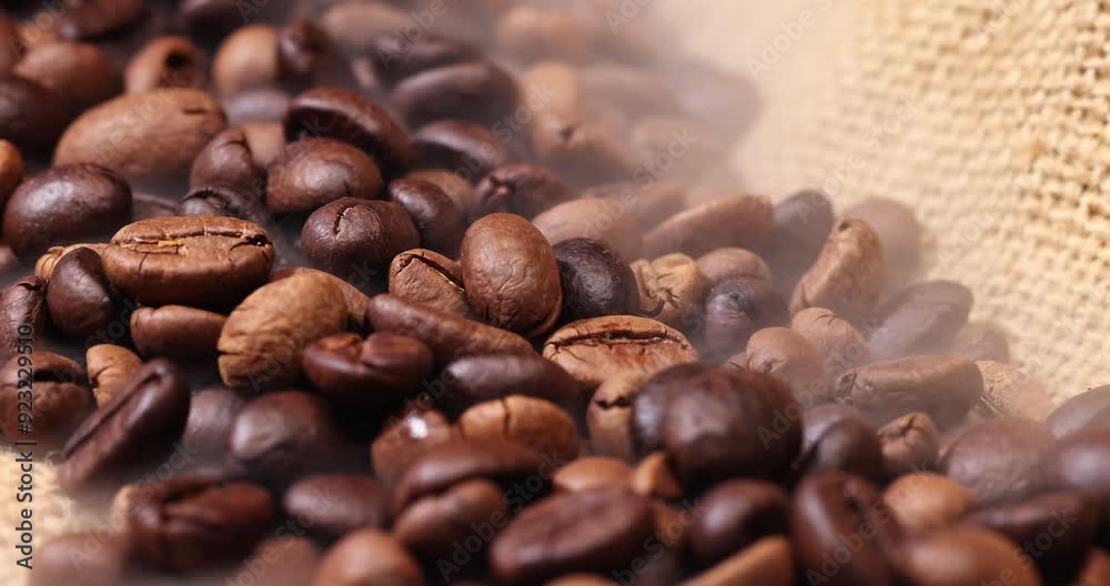 Dark brown Coffee bean macro closeup flow move fall drop pan roll smoking roasting cooking transparent clear glass cup saucer pour liquid on jute fabric background Dark brown Coffee bean macro closeup flow move fall drop pan roll smoking roasting cooking transparent clear glass cup saucer pour liquid on jute fabric background