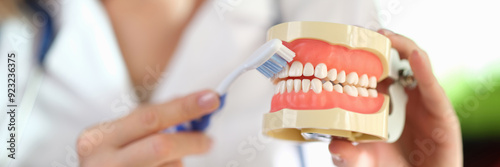 Doctor stomatologist showing how to brush teeth properly