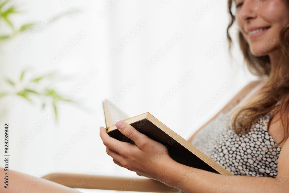 Young girl reading an interesting book. Young woman entertains herself by reading a book. She smiles because she likes the story of the book and imagines the protagonists. Young girl reading an interesting book. Young woman entertains herself by reading a book. She smiles because she likes the story of the book and imagines the protagonists.