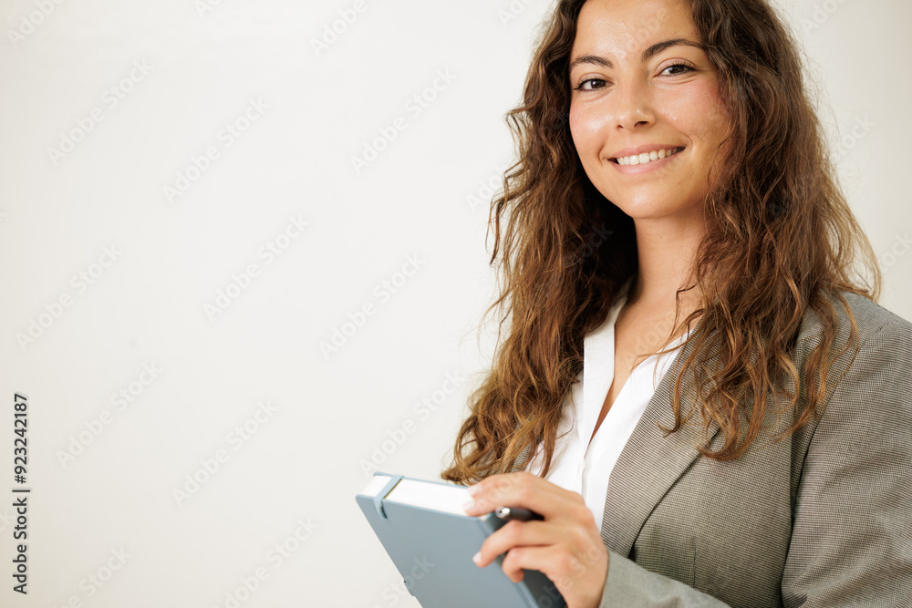 Teacher or young businesswoman has her agenda in her hands. She is going to present the work organization in front of her team. She smiles at the camera. Copy space. Close up.