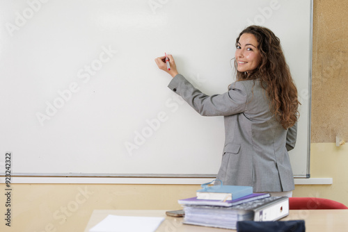A teacher writing the new agenda for the day on the class blackboard. A businesswoman at the office board to propose her idea in team work. Young woman smiles looking at camera.