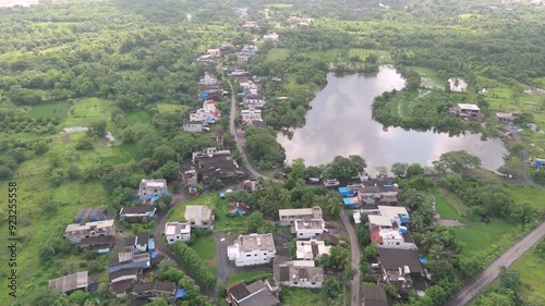 Aerial view of village near pond. Drone shot of pond surrounded by village homes. photo