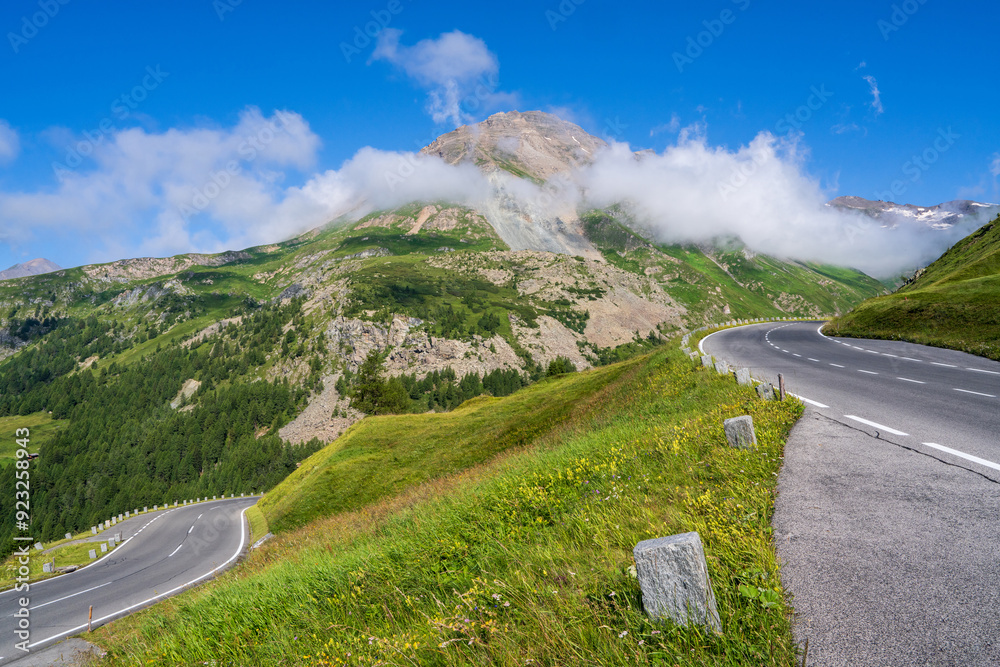 Obraz premium Winding alpine road Grossglockner. Beautiful mountain landscape. Clouds descend on high cliffs. Clear sunny day. Grossglockner high alpine road. Hohe Tauern National Park. Austria