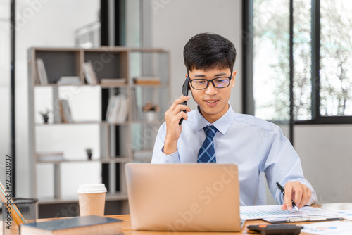 Young besinessman talking on the phone while working at his office