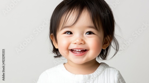 Portrait of a baby girl with big, dark eyes and smooth black hair, gazing curiously at the camera.