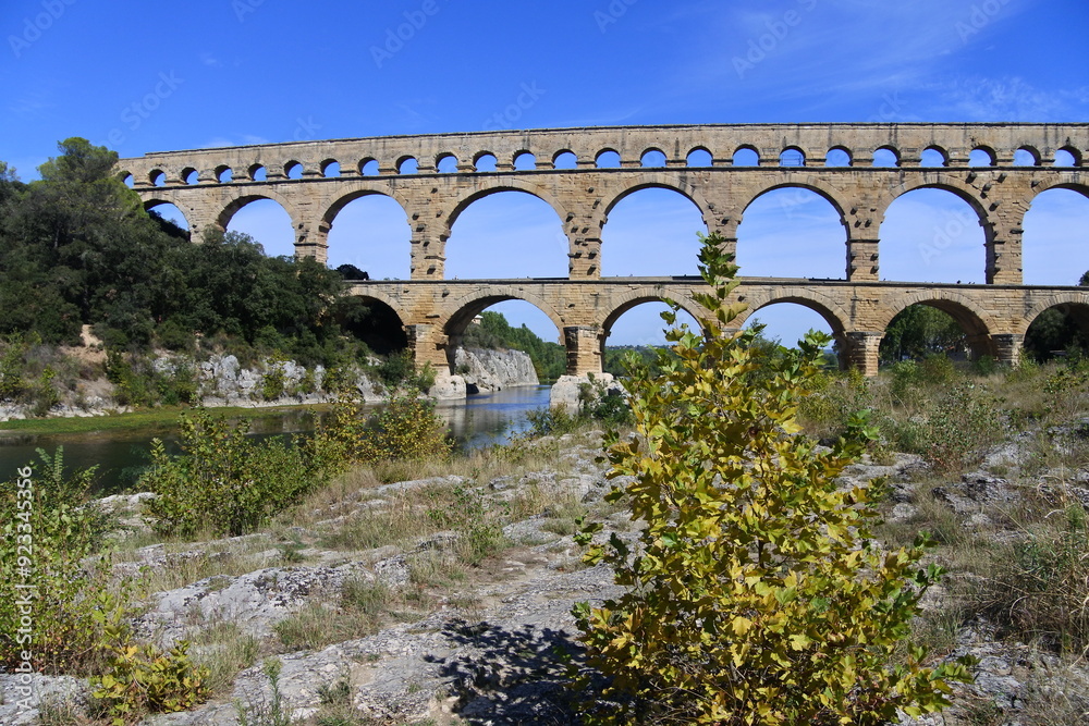 Fototapeta premium Blauer Himmel, der Pont du Gard und ein Fluss 