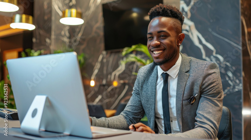 Cheerful black man checking in at a modern hotel reception desk.