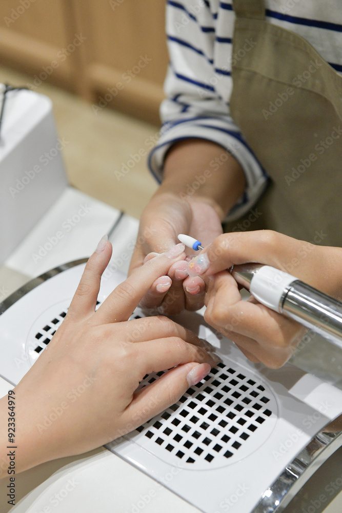 A person receiving a manicure, showcasing a relaxed and pampered expression. The hands are well-groomed, and the setting is a nail salon. A person receiving a manicure, showcasing a relaxed and pampered expression. The hands are well-groomed, and the setting is a nail salon.