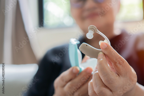 Technology that gives better sense of sound, speach. Hearing aids in hands of happy old woman