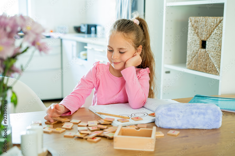 Cute 6 year old little girl doing homework at home in the kitchen at the table. Back to school. Educational games. Cute 6 year old little girl doing homework at home in the kitchen at the table. Back to school. Educational games.