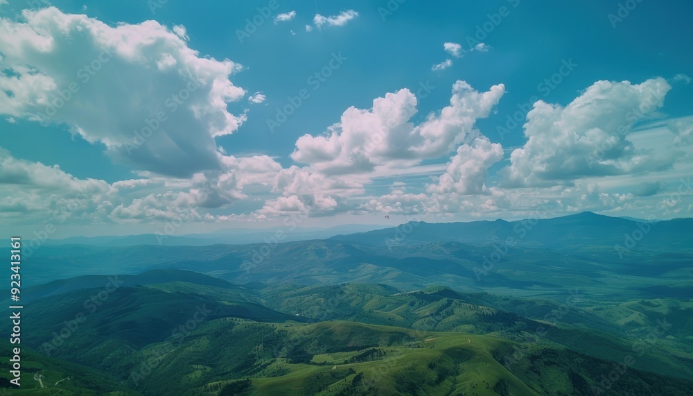 Expansive mountain view under a bright sky with fluffy clouds in daytime Expansive mountain view under a bright sky with fluffy clouds in daytime