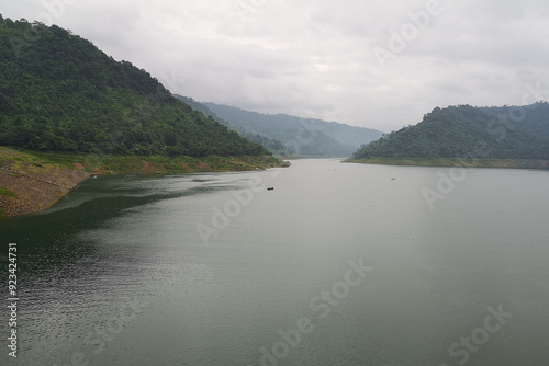 Scenic view of a mountain river flowing through a lush green forest with reflections in the water and surrounding mountains