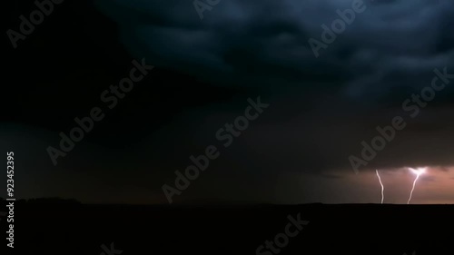 A lightning bolts cut through dark clouds during a night storm, creating a dramatic and intense atmospheric scene.