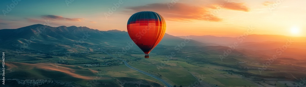 Obraz premium A colorful hot air balloon soaring over a scenic landscape at sunset.