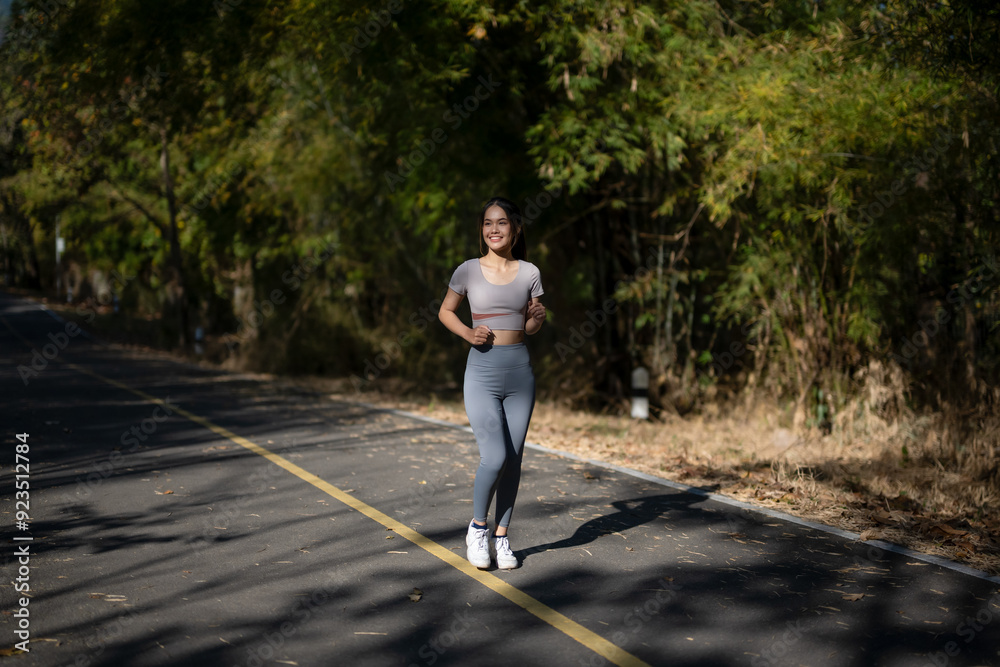 A woman is running on a road with trees in the background A woman is running on a road with trees in the background